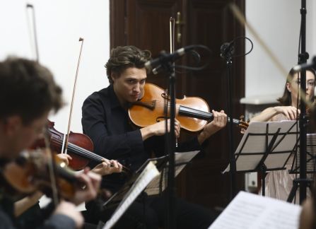 A photograph. A string concert in Villa Decius. The musicians play the violin and the cello in the Ball Room at Villa Decius.